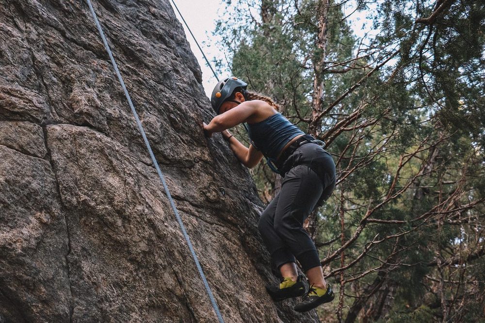 A student rock climbing on a cliff face overlooking a canyon