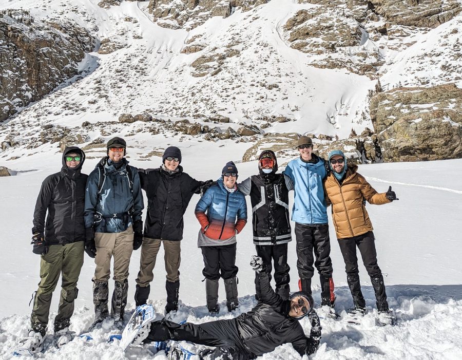A group photo on snowshoes in front of jagged snowy peaks