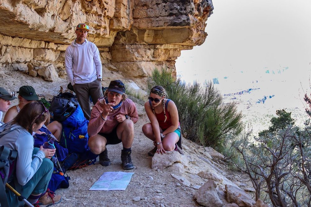 Students discussing a map together on a canyon overlook
