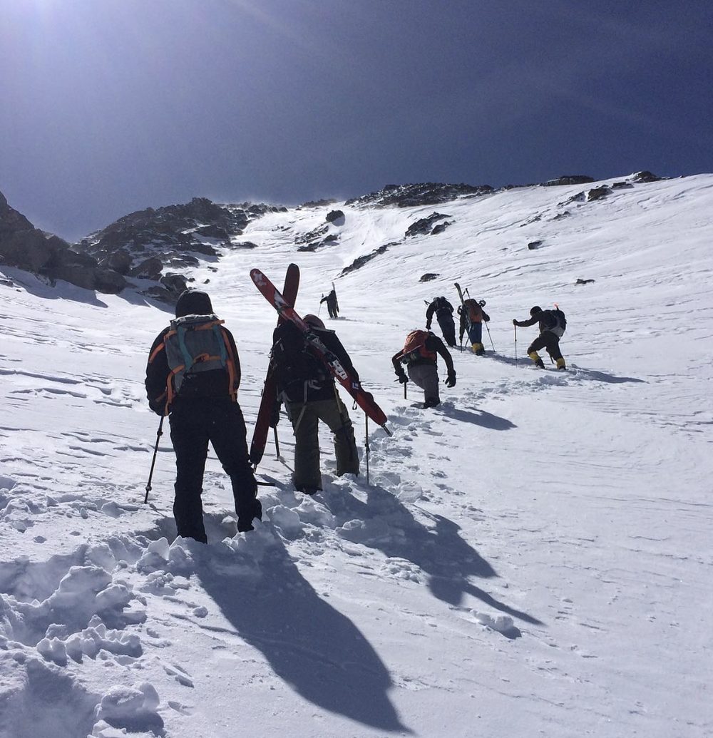 A group of skiers skinning up a steep snow slope