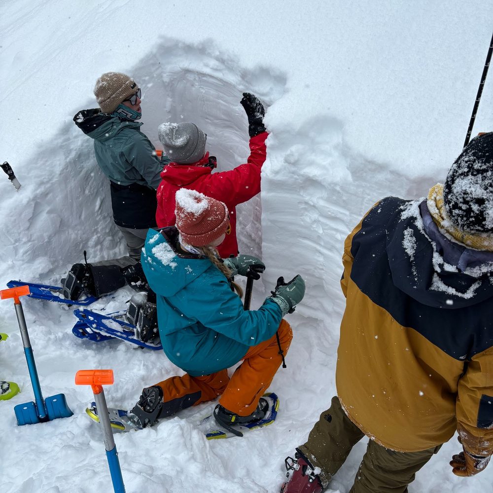 Two students digging a snow pit to assess avalanche danger