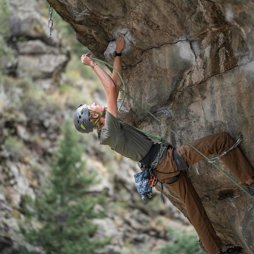 A student lead climbing on an overhanging rock face